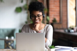 Young black woman wearing headphones and learning on laptop