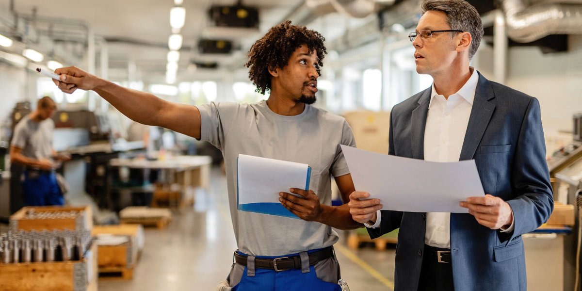 Worker discussing the workplace violence training action plan with manager while touring industrial facility