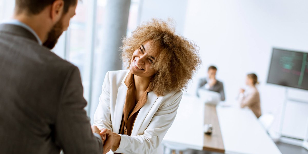 two business people shaking hands, smiling, and demonstrating ethical behavior in the workplace