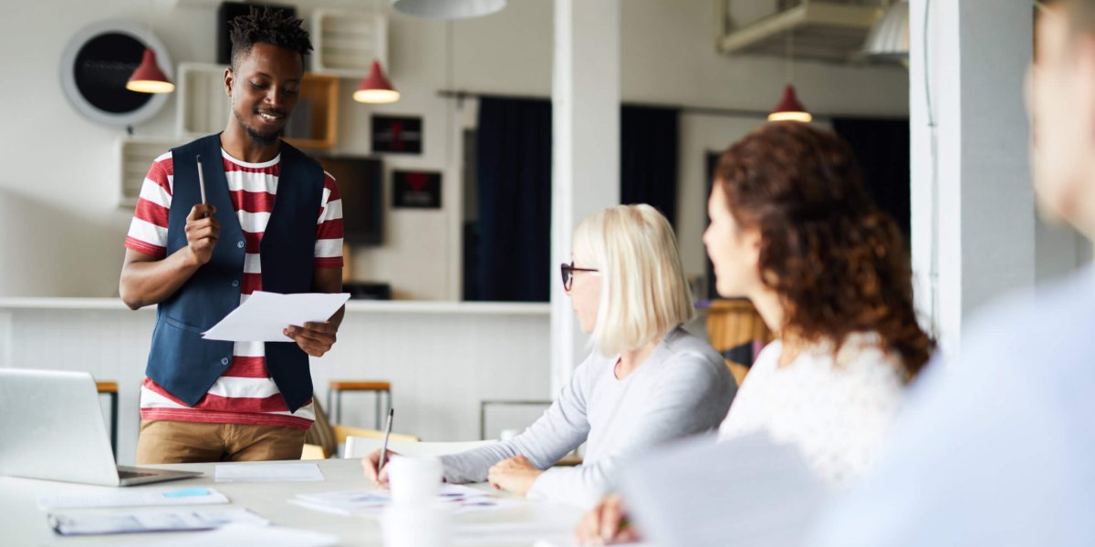 Young black employee presents to diverse work group in training session