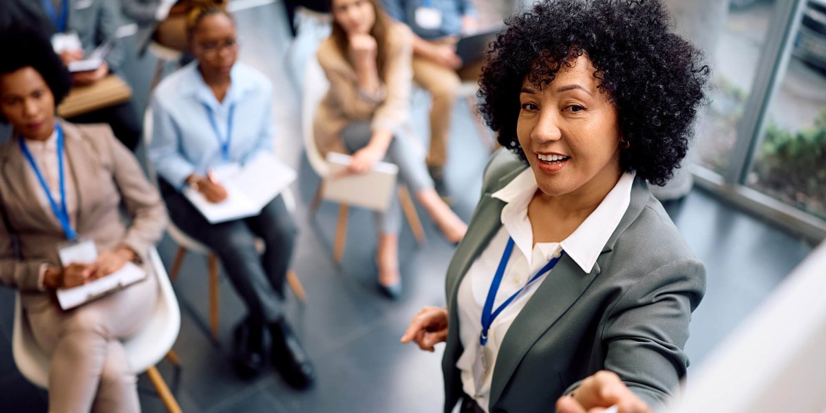 Female Trainer standing at whiteboard reviewing California Compliance Workplace Training Programs with corporate audience