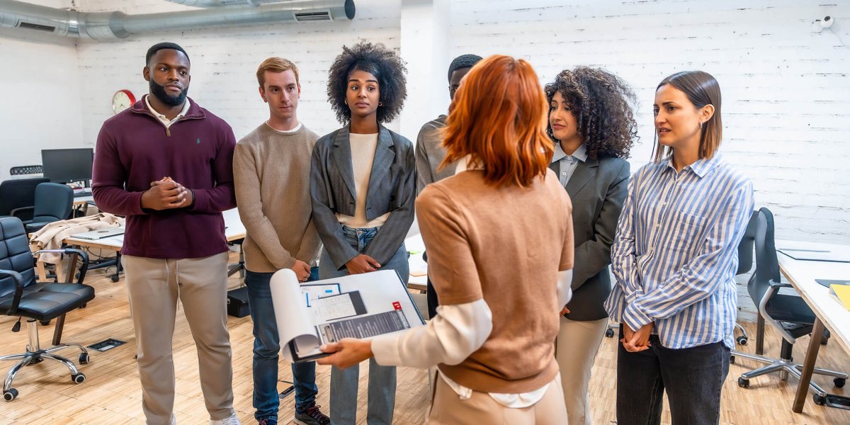 Female trainer standing and reviewing violence in the workplace training with diverse group of employees