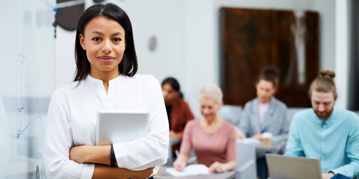 female presenter in corporate office conducting sexual harassment training to diverse employee team at desks
